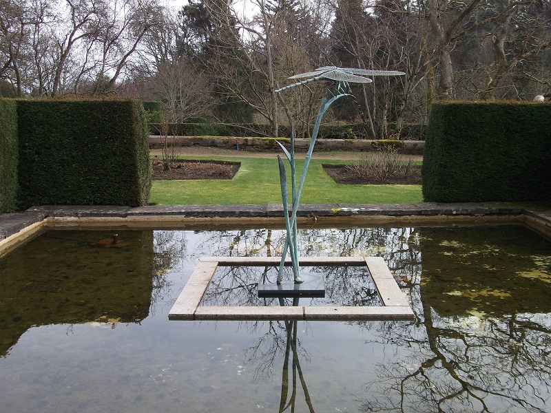 A sculpture of a bird, in a pond