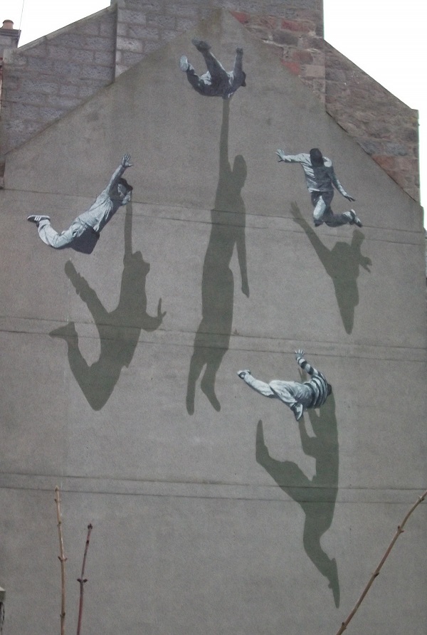 Street art featuring jumping men with large shadows creating a 3D effect