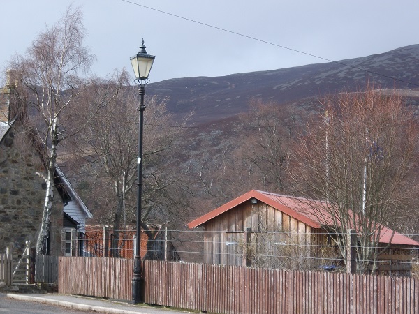 A mountain behind a Victorian streetlamp and a wooden hut