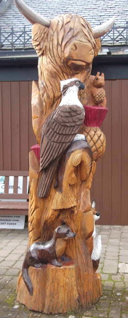 A wooden highland cow with bird of prey, fox, otter and squirrel