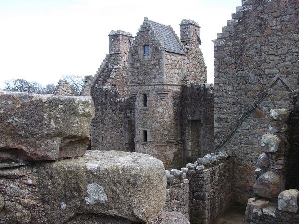 a castle tower with with windows surrounded by ruins