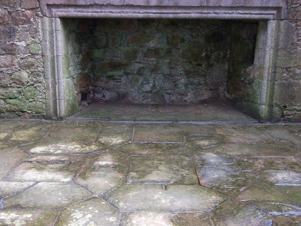 a large fireplace in front of a floor of hexagonal and square sandstone flags