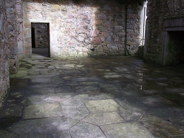 a floor of hexagonal and square sandstone flags surrounded by brick walls 
