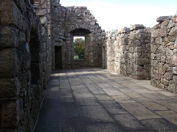 A paved room with large window and ruined walls