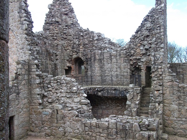 A ruins of a castle tower, with steps to a half remaining upper floor and walls that tower above